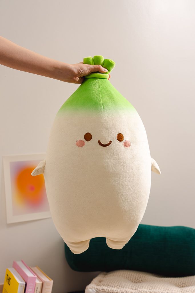 An arm holding a Daikon radish-shaped plushie with a cute face.