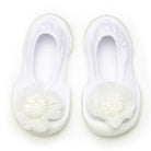 A pair of white baby shoes with a flower design.