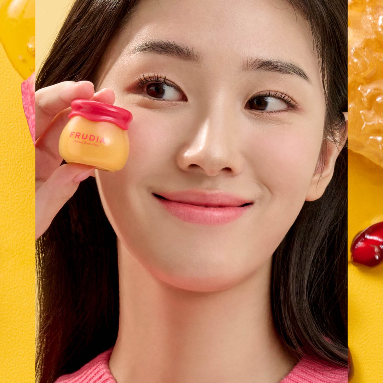 A woman holding a Frudia skincare product.