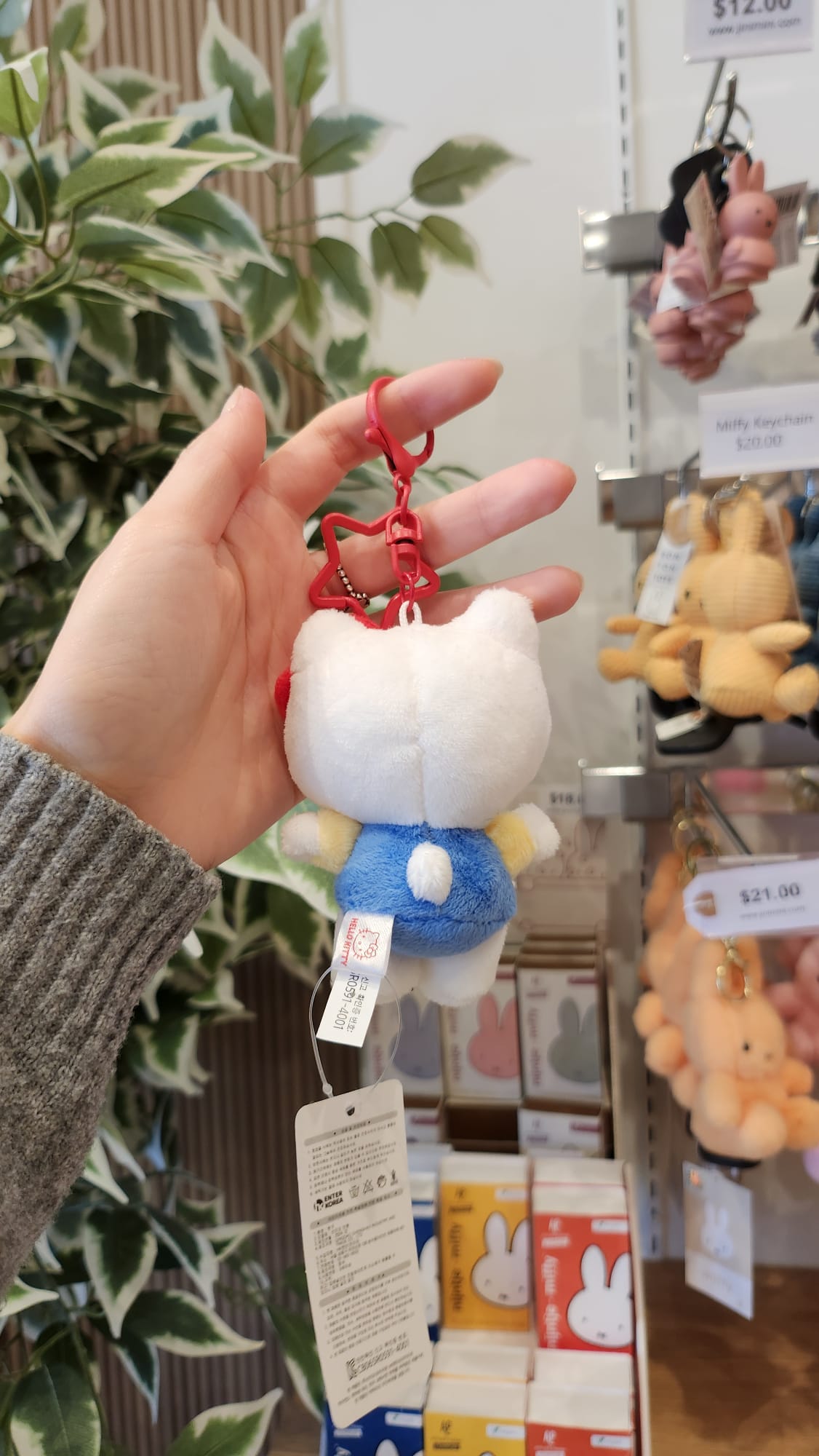 A hand holding a Hello Kitty plush keychain with a red star-shaped clip.