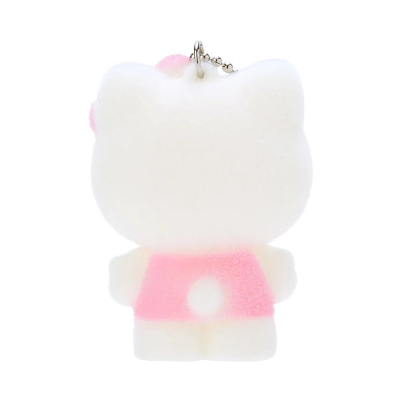Back view of a fluffy white Hello Kitty keychain wearing a pink dress.