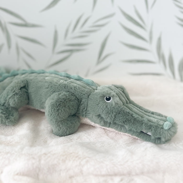 Plush toy alligator on a soft surface with a light background