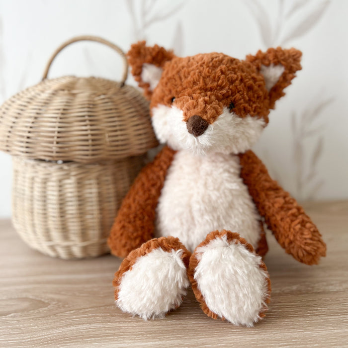 Stuffed fox sitting next to a mushroom-shaped wicker basket.