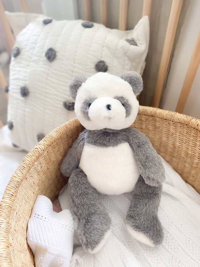 Stuffed gray and white panda toy in wicker basket.