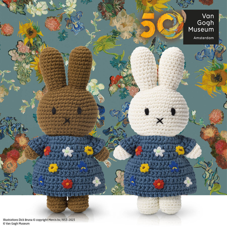 Two crocheted Miffy rabbit dolls in blue floral dresses against a floral background.