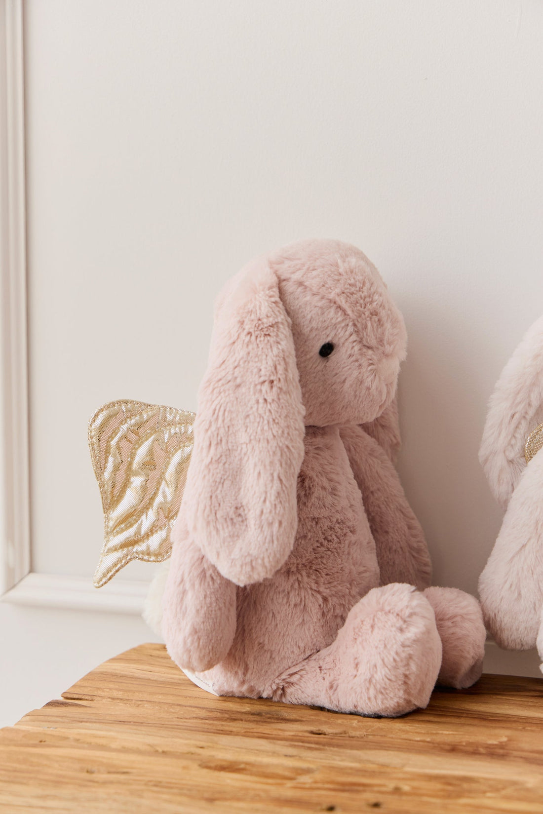 Pink plush bunny toy with golden wings.