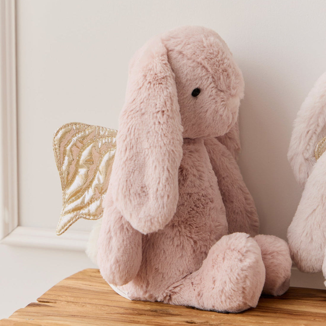 Pink plush bunny toy with golden wings.