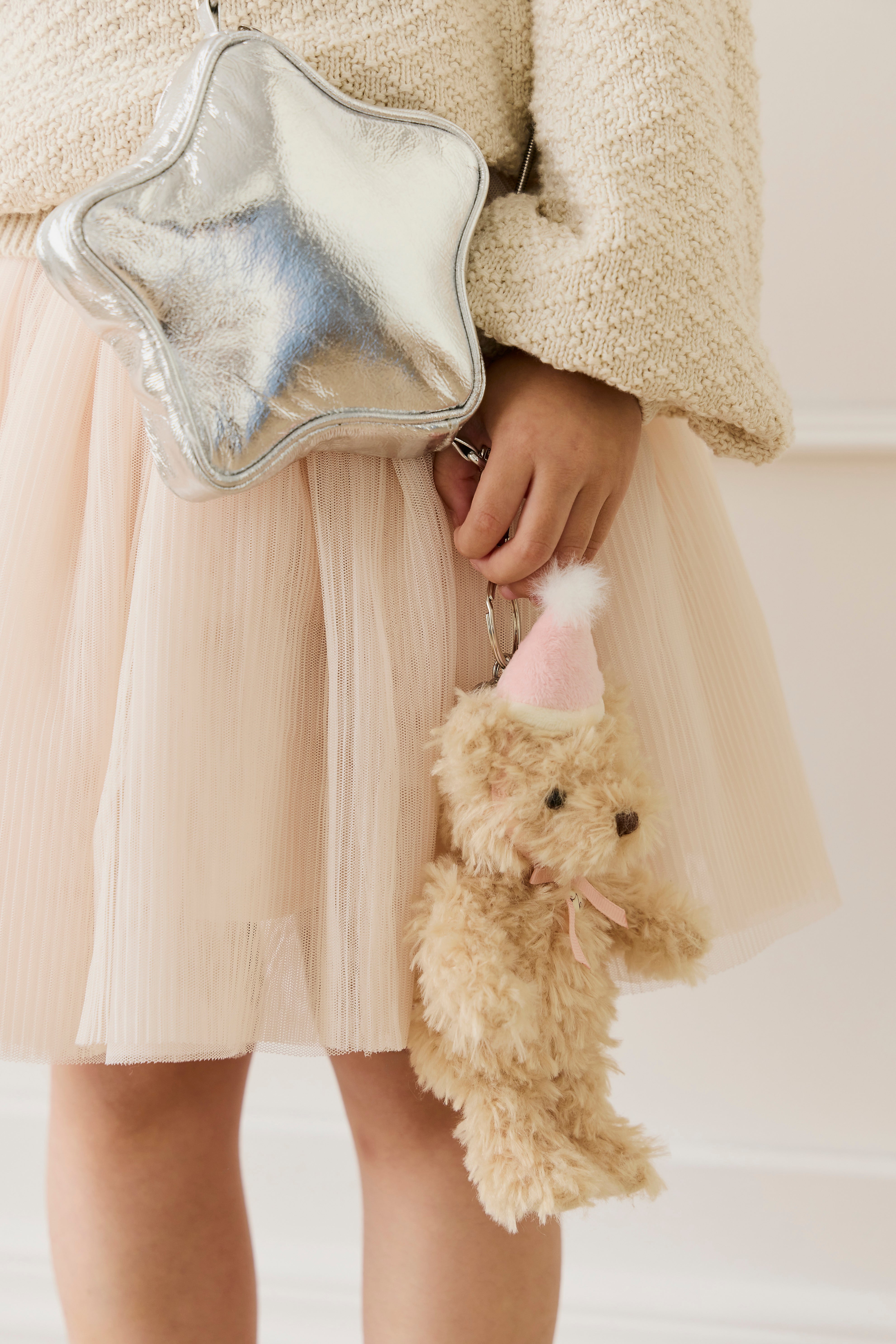 Person holding a silver star-shaped bag and a small teddy bear.