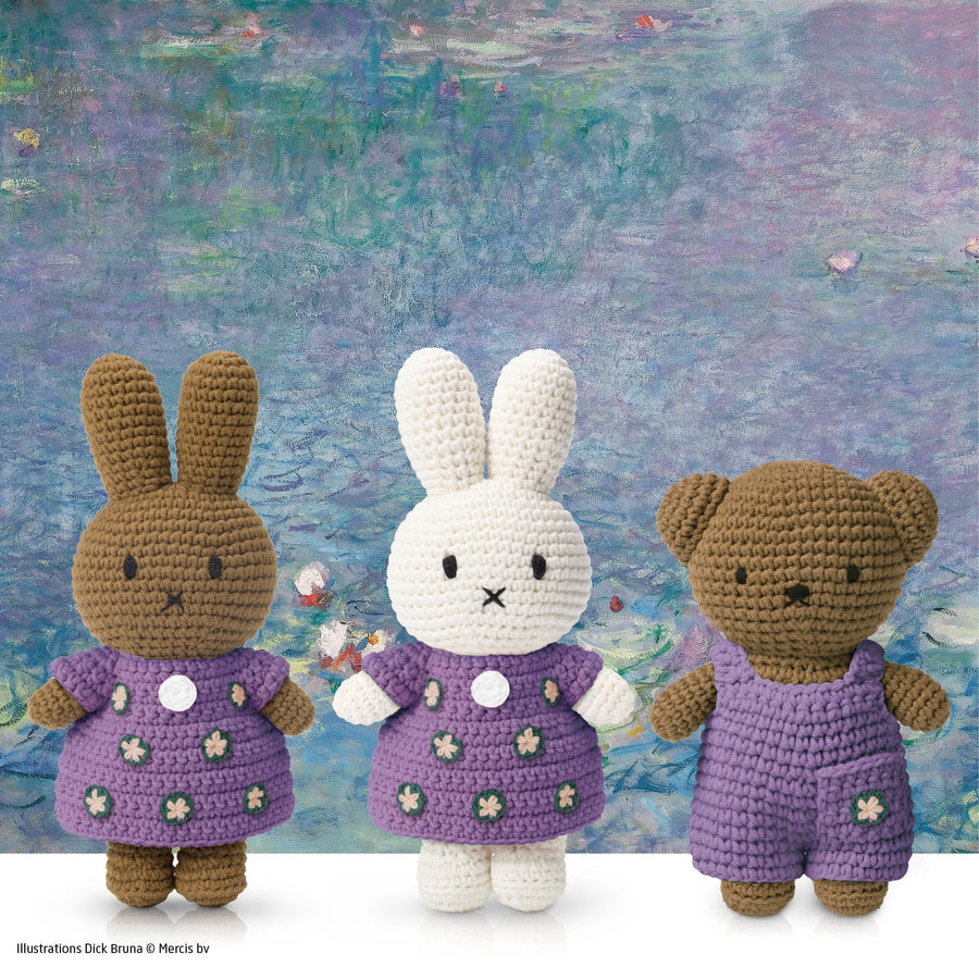 Three crocheted stuffed animals (two rabbits, one bear) wearing purple clothes in front of a Monet water lilies painting.