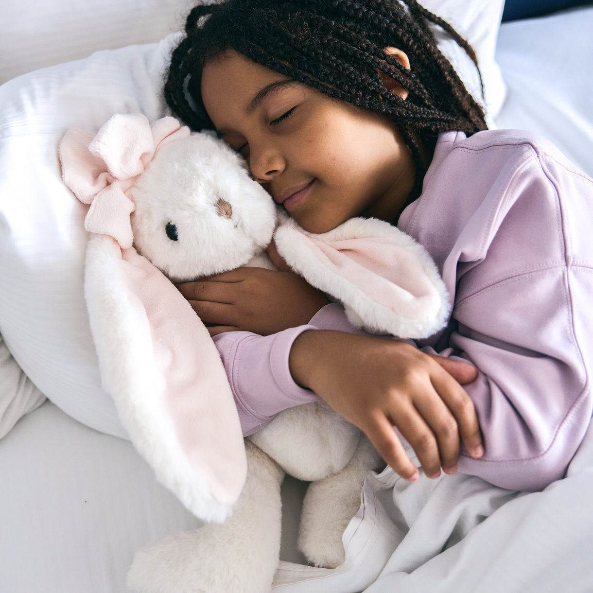 Child sleeping with a plush bunny toy in a cozy setting