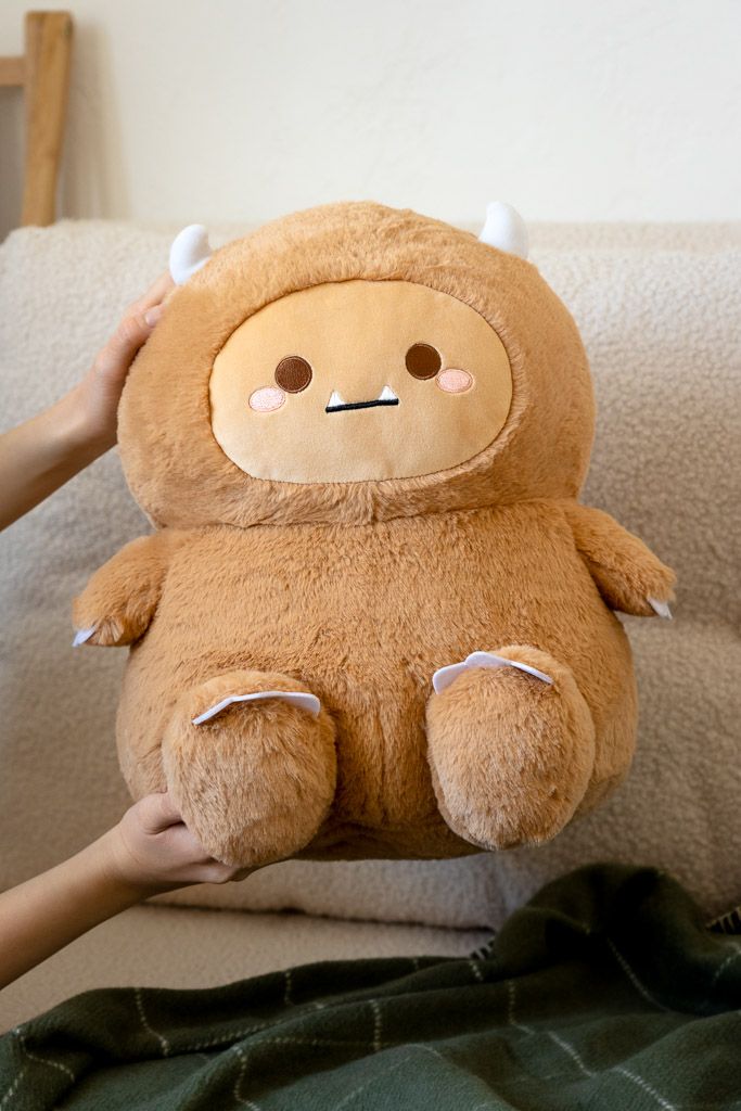 Brown plush monster toy with small white horns.