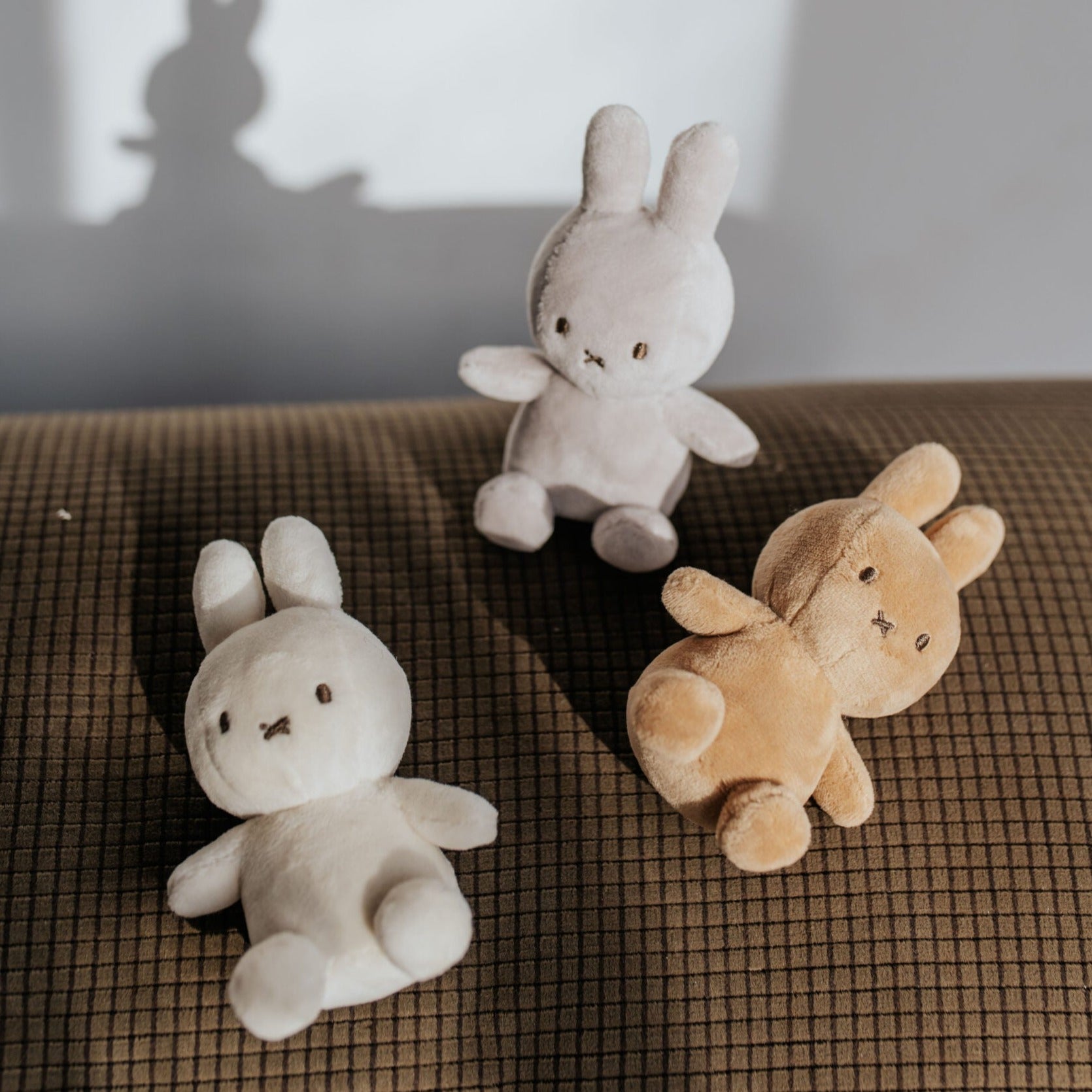 Three plush bunny toys on a brown textured surface.