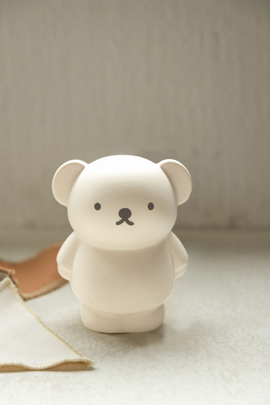 An off-white, Miffy-style bear figurine with a simple black nose and eyes.