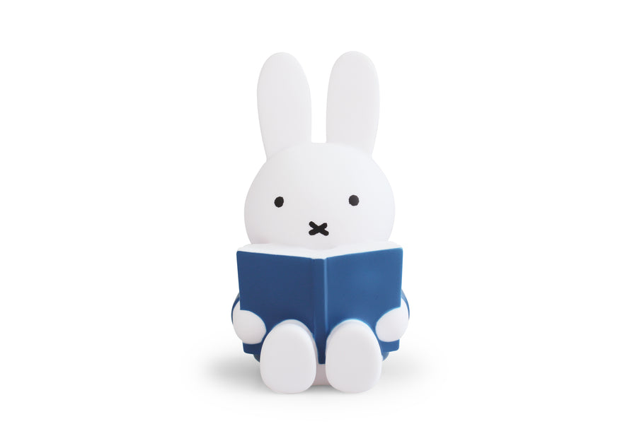 White Miffy-shaped lamp reading blue book.