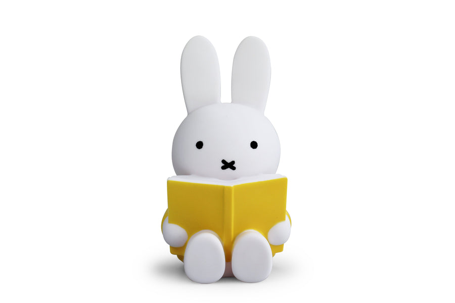 White Miffy rabbit lamp reading a yellow book.