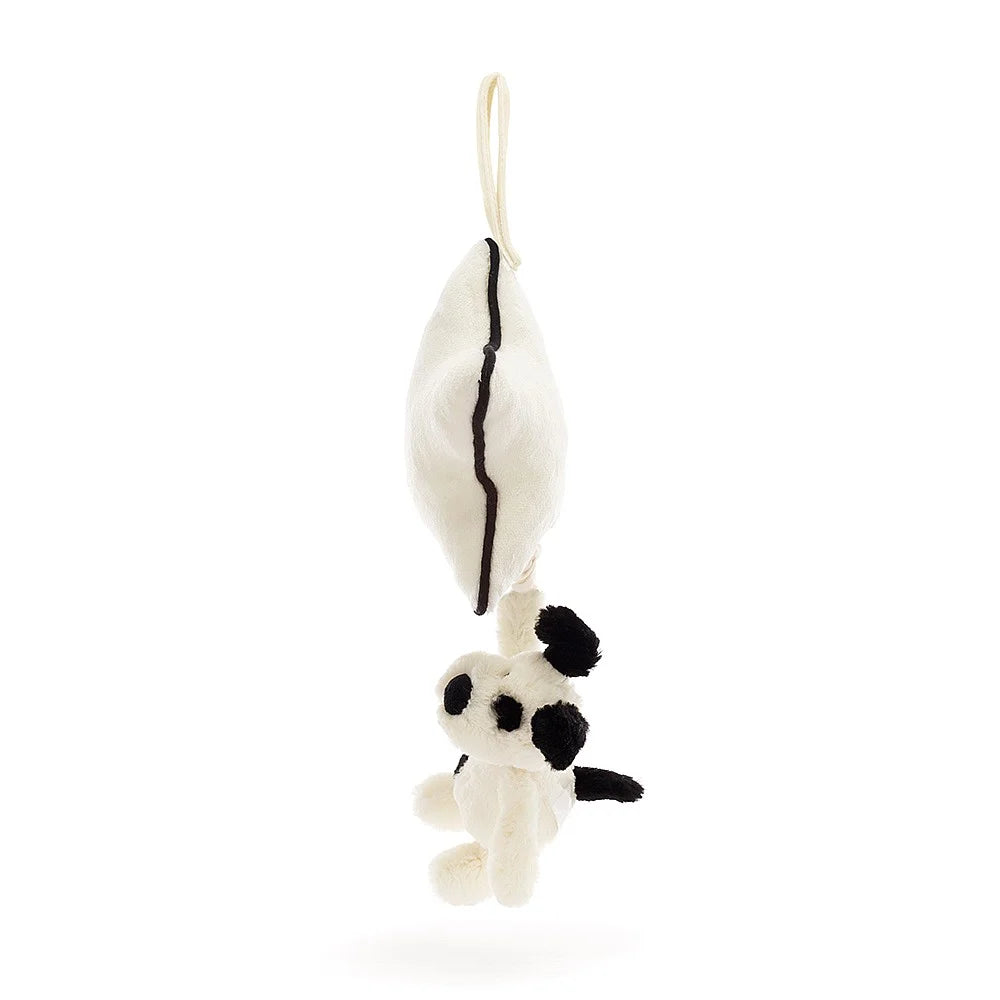 Stuffed white dog toy with black spots hanging from a white pillow with a black outline.