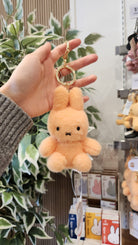 Hand holding an orange Miffy plush keychain.