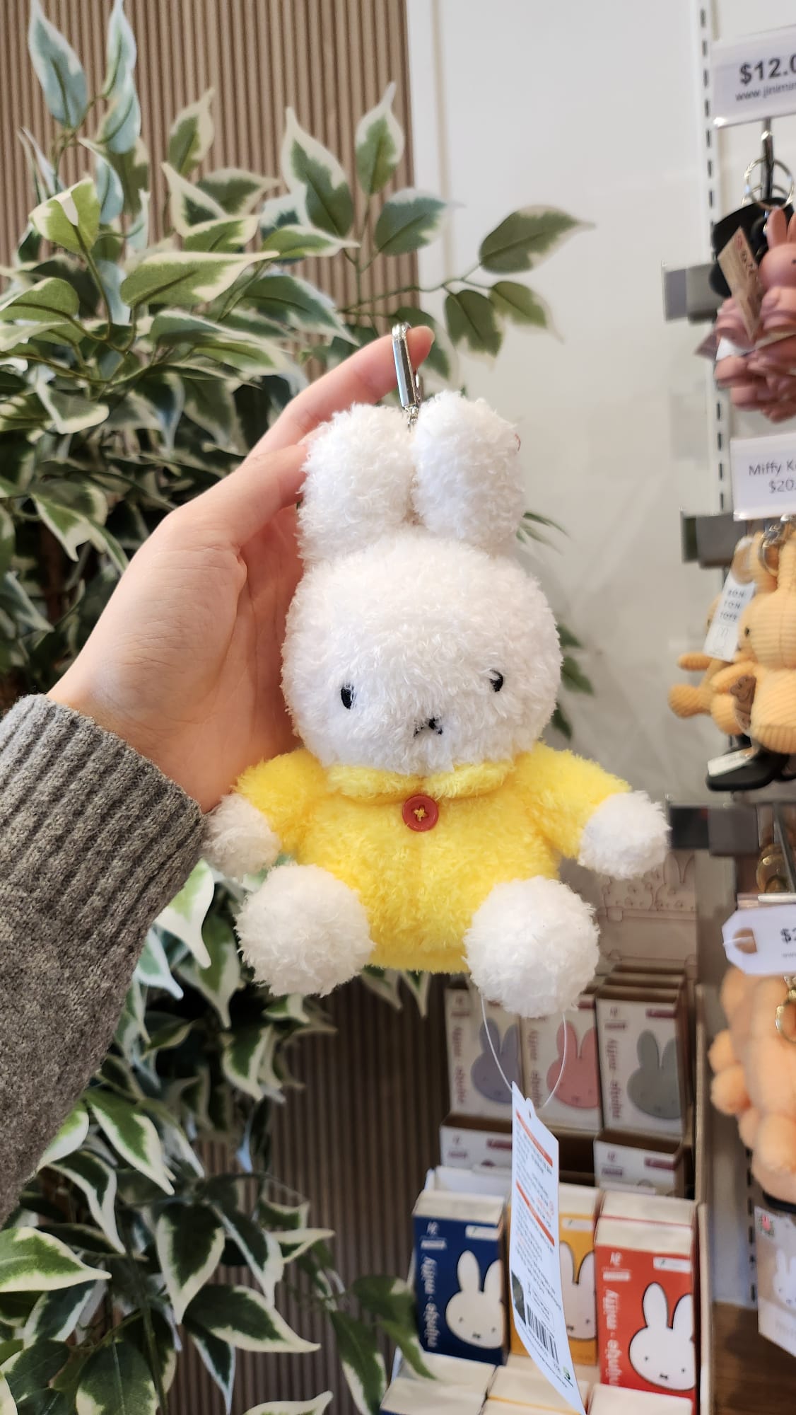 A hand holding a white and yellow Miffy bunny keychain.