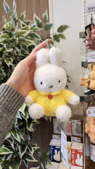 A hand holding a white and yellow Miffy bunny keychain.