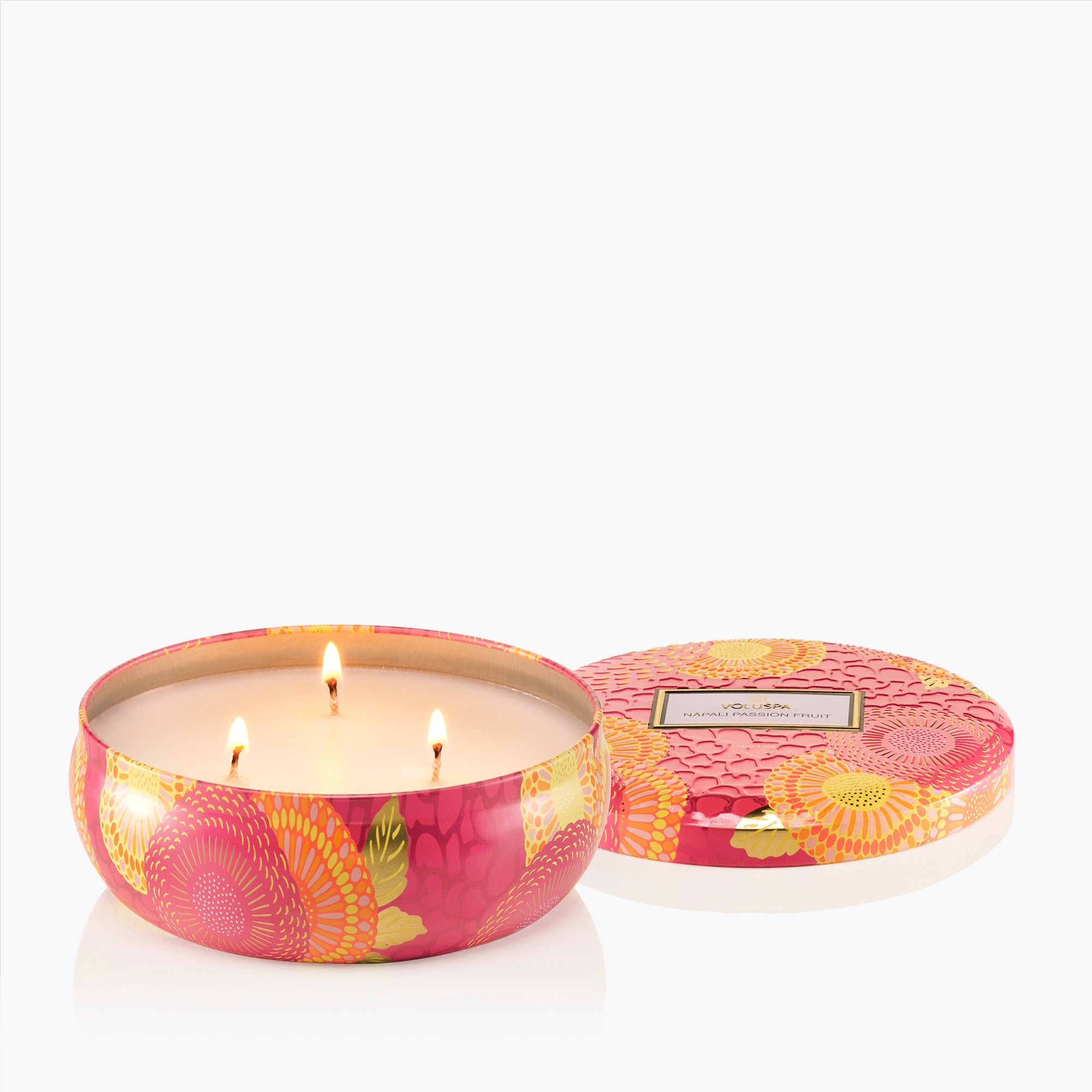 Pink floral candle in a decorative tin with lid on a white background