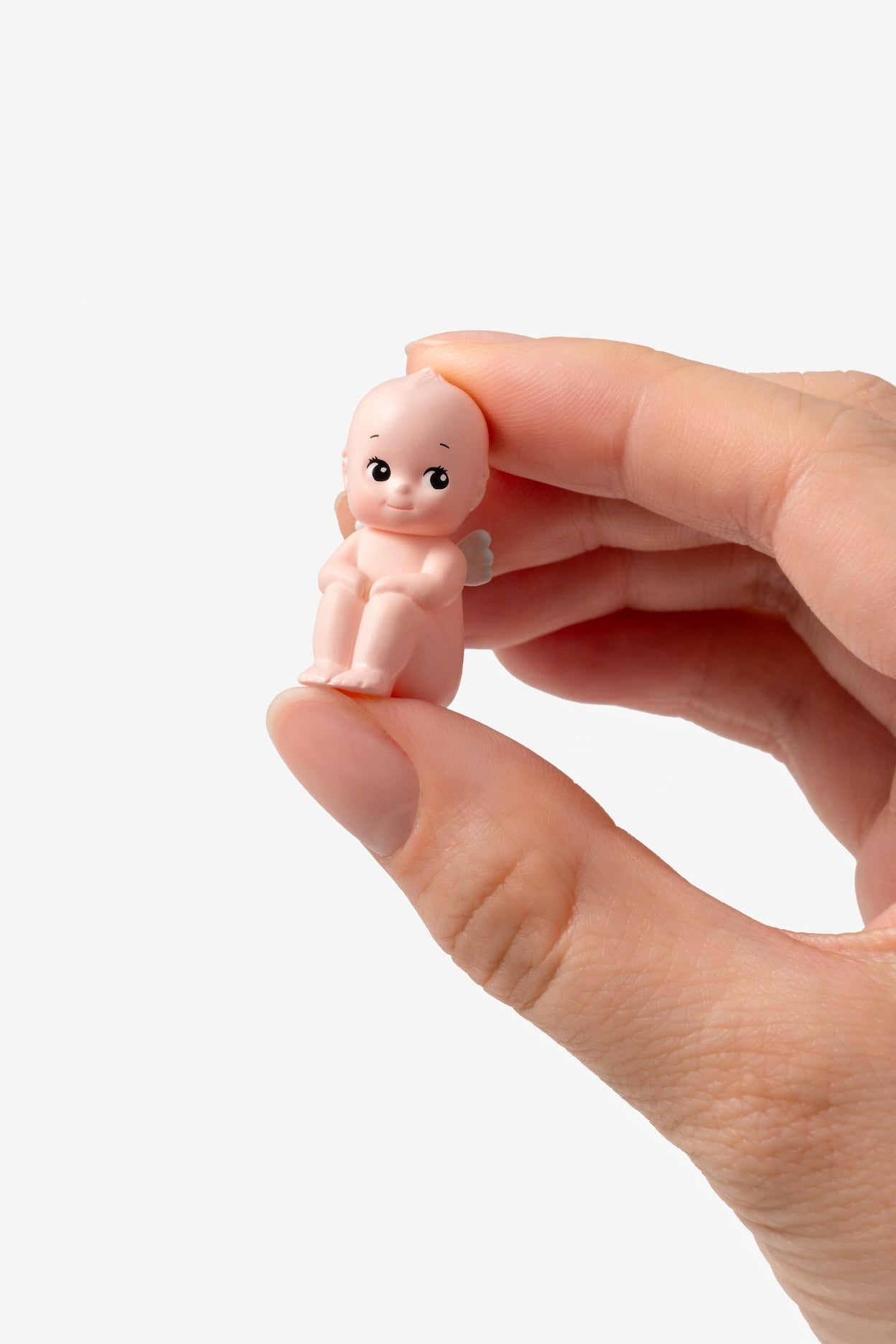 Hand holding a small baby figurine against a white background