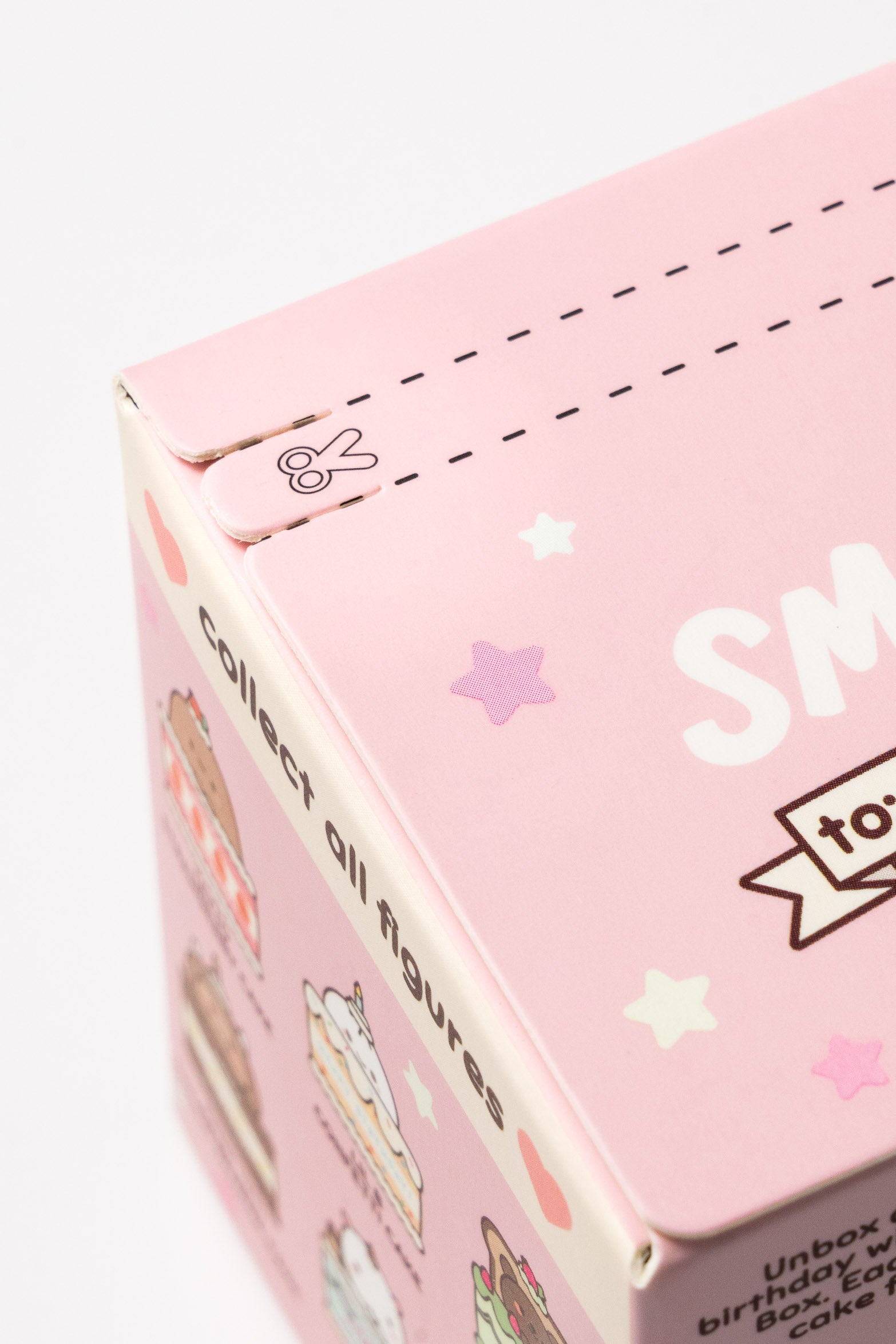 Close-up of a pink box with dotted lines, a scissors graphic, and illustrations of cakes and stars.