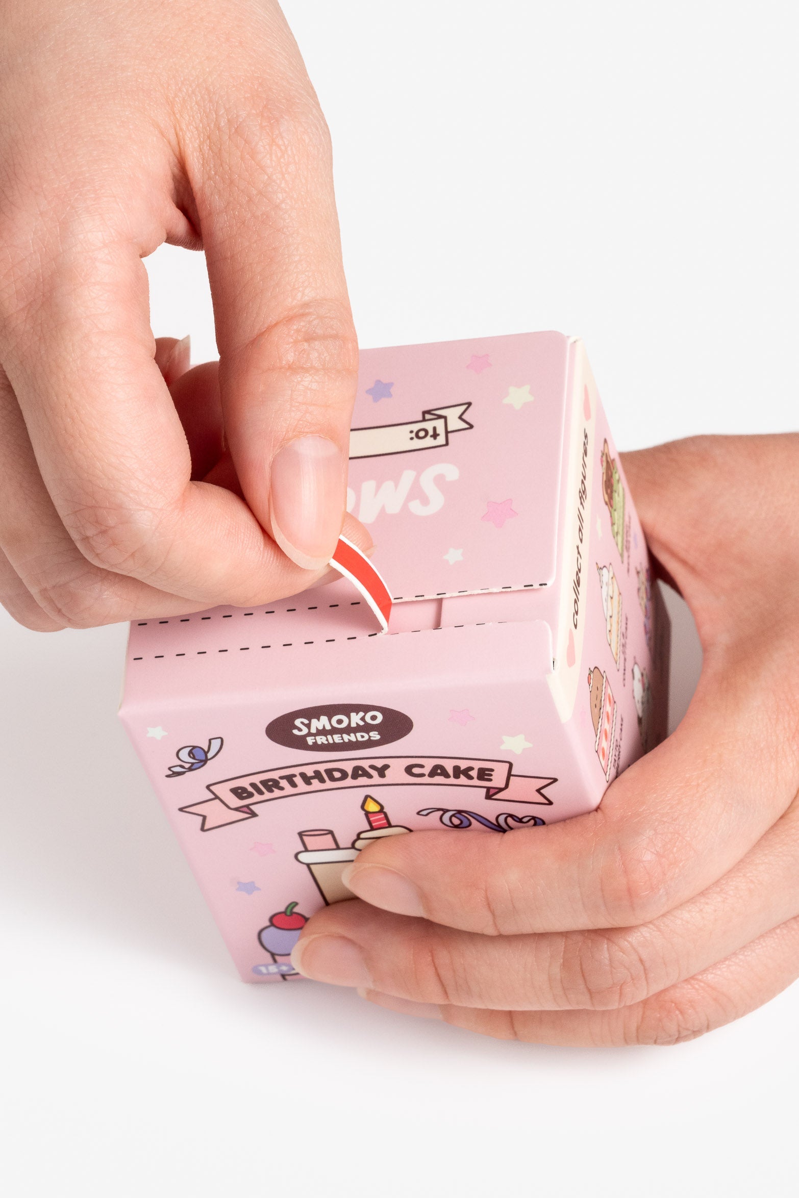 Hands opening a pink Smoko Friends Birthday Cake toy box.