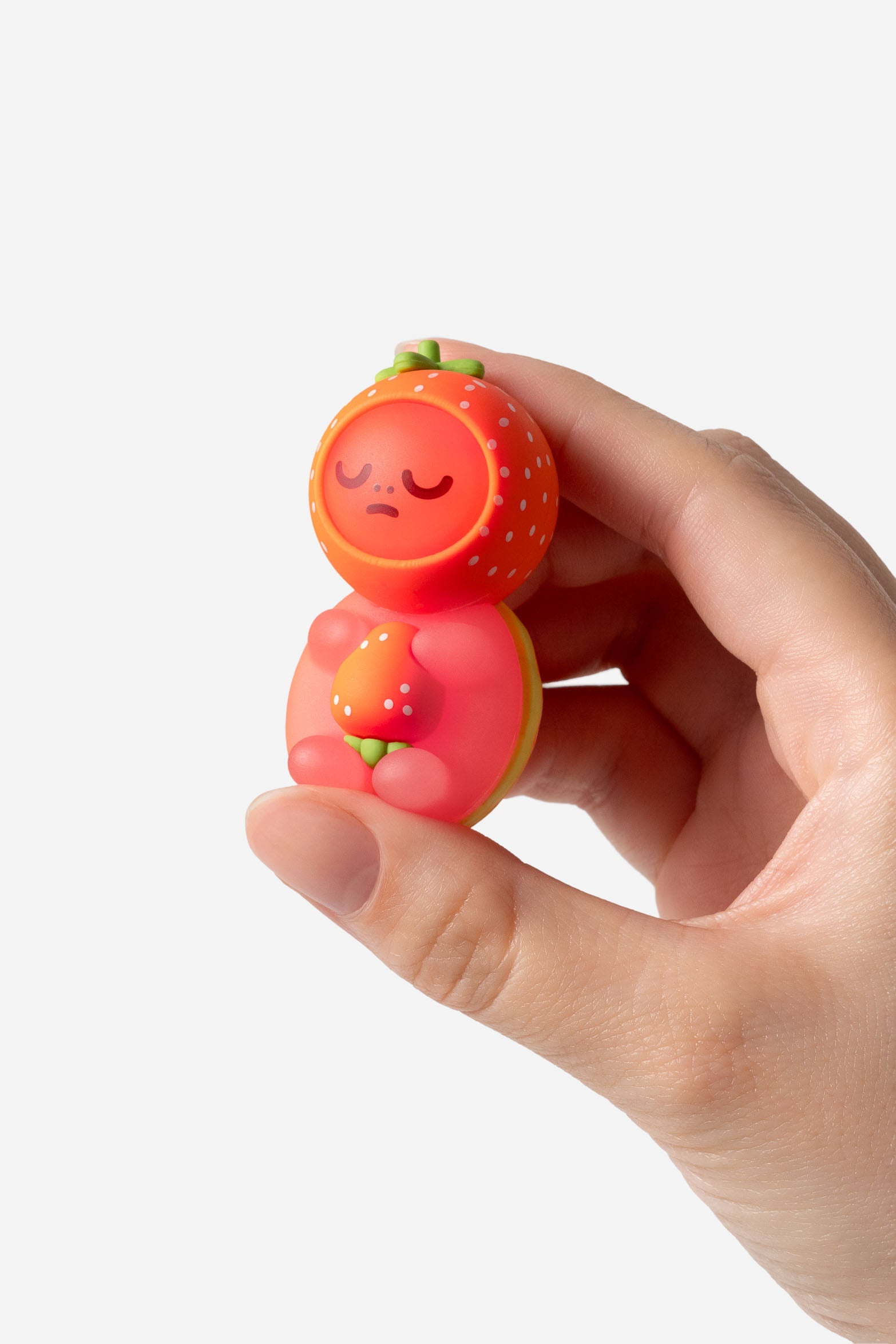 Hand holding a strawberry-themed collectible toy.