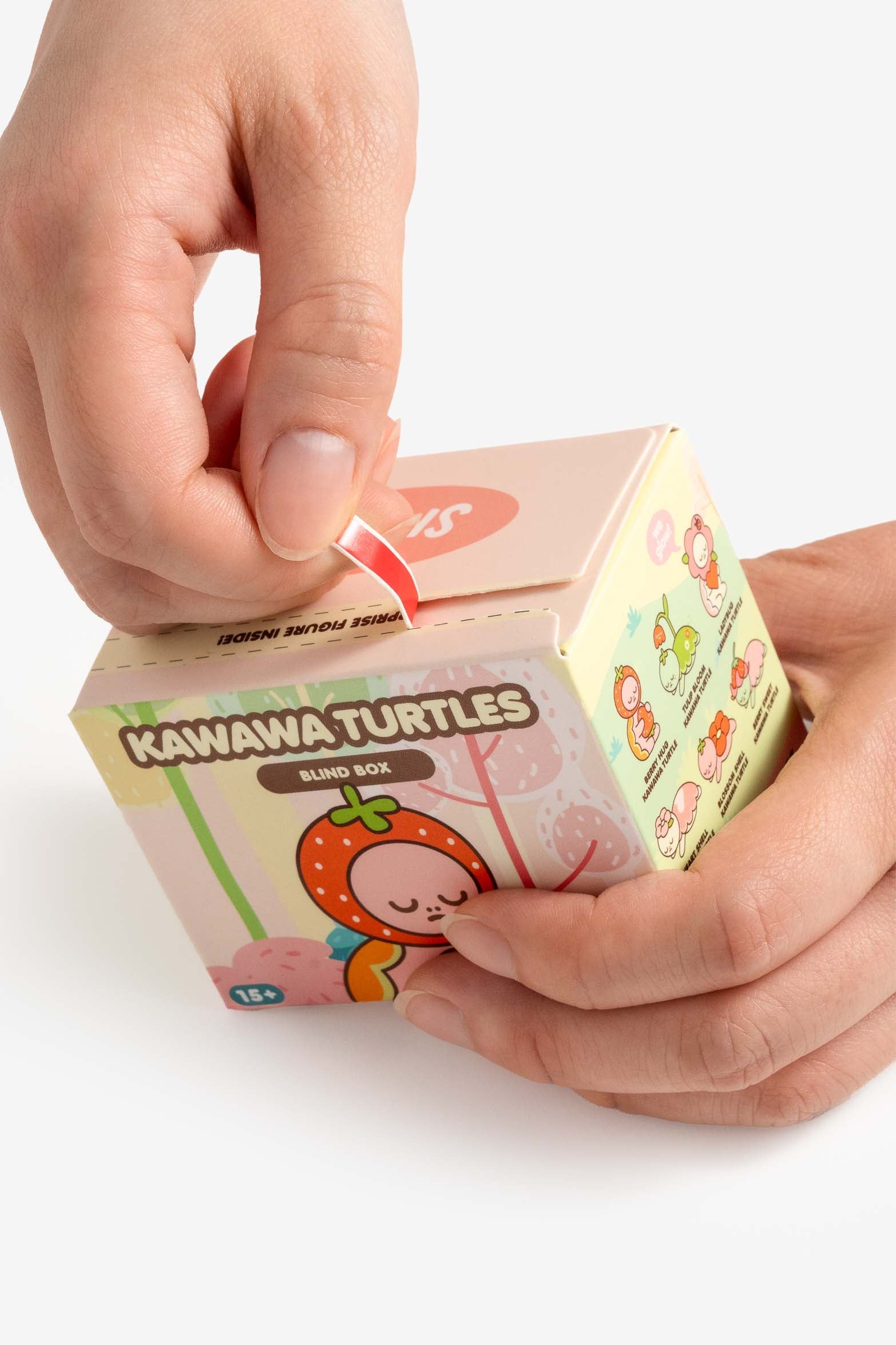 Hands opening a Kawawa Turtles blind box with a red seal.