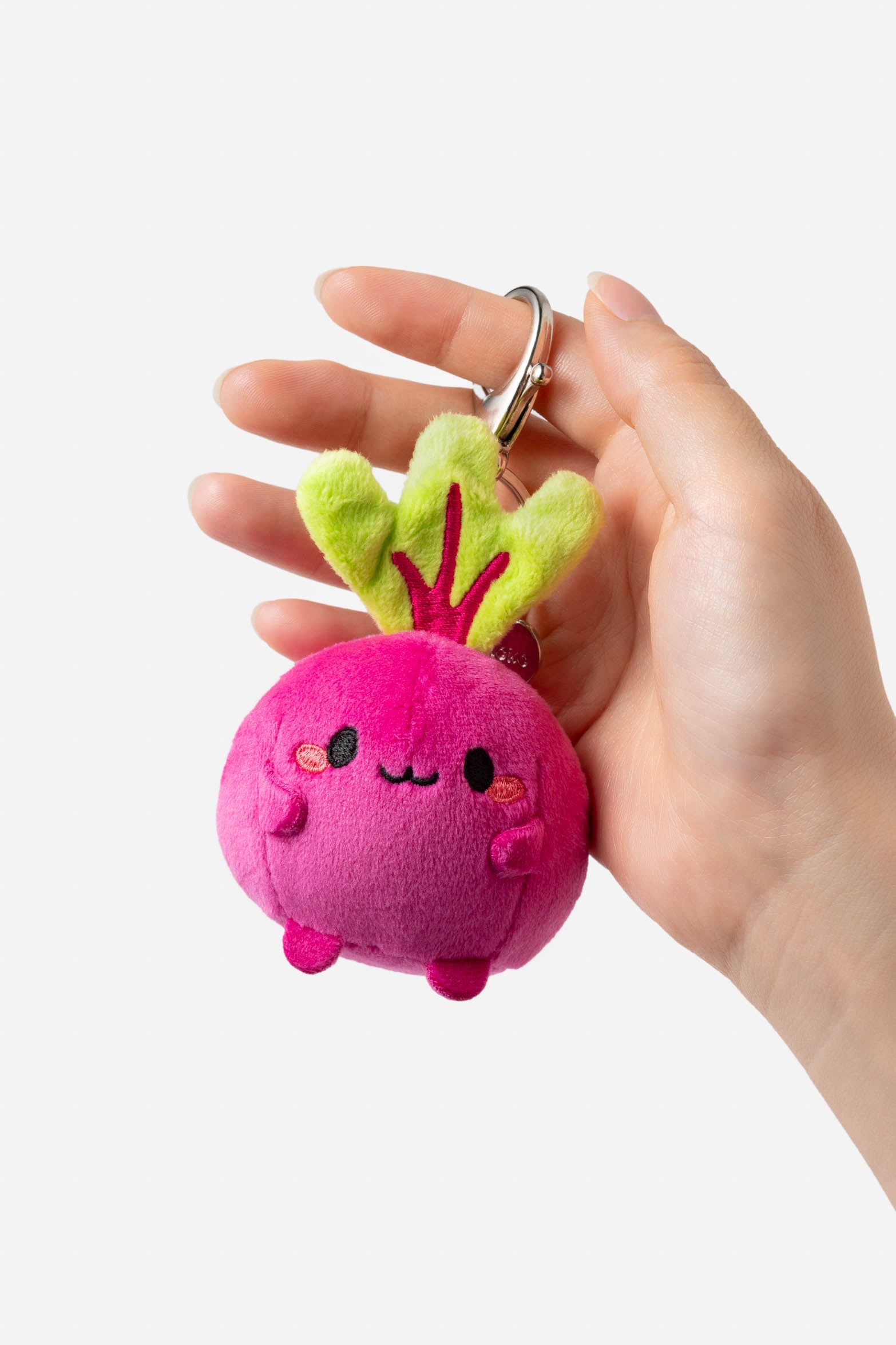 Hand holding a pink plush beet keychain.