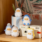 Set of cartoon shark figurines on a shelf with a retro camera and tropical-themed fabric in the background.