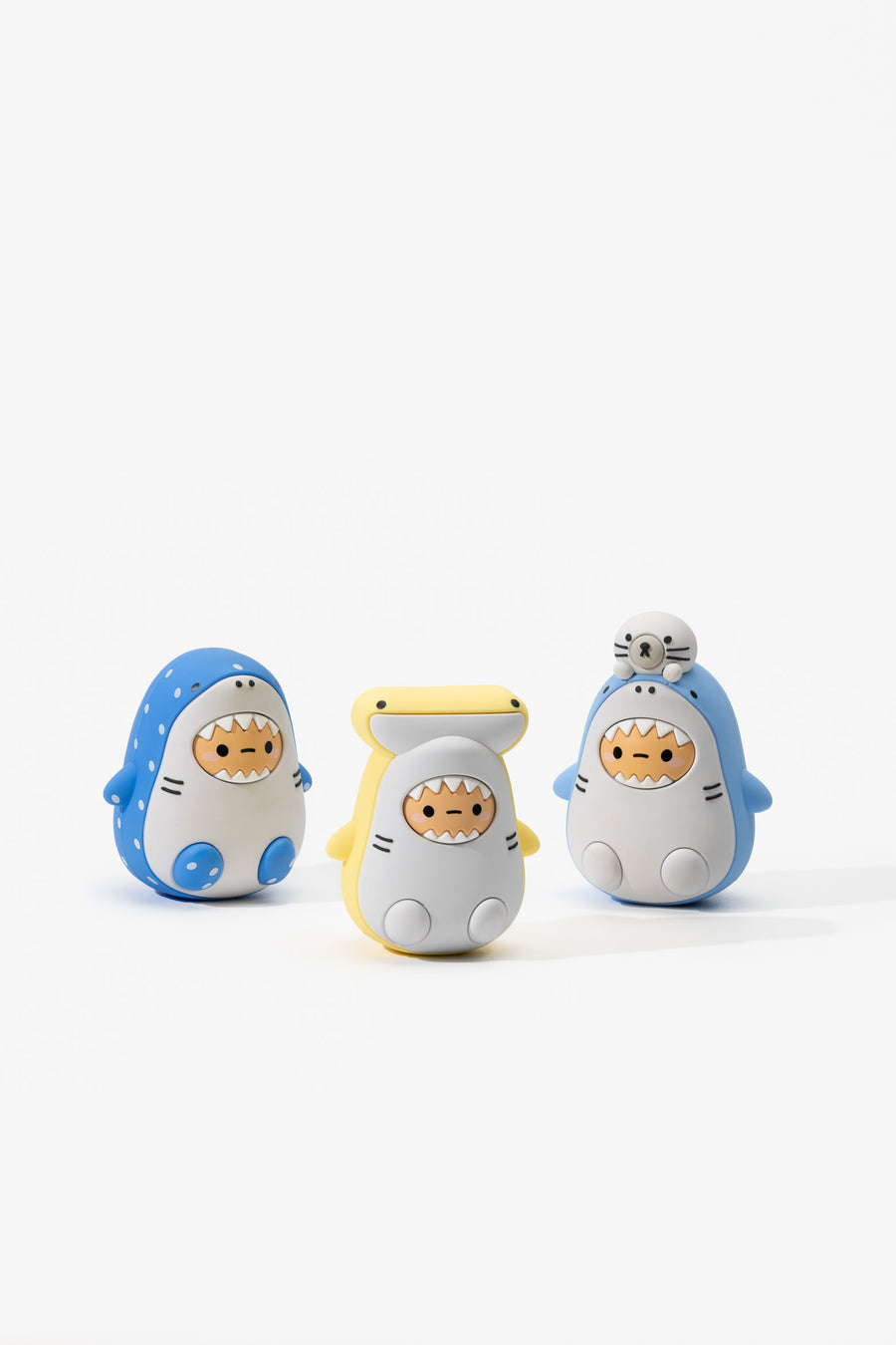 Three cartoon shark figurines with different colors on a white background