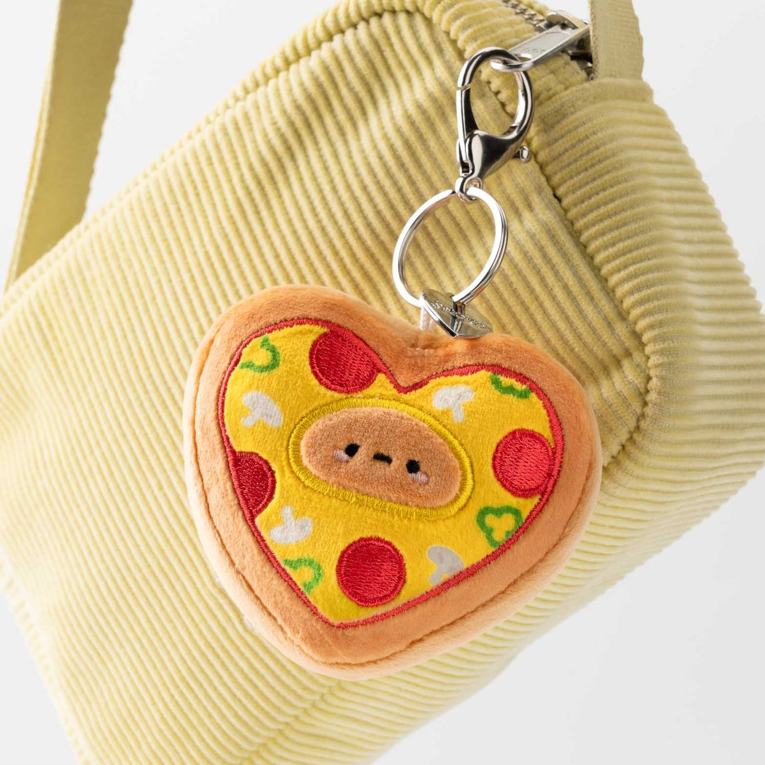 Yellow corduroy purse with heart-shaped pizza keychain.