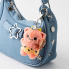 Light blue denim purse with a furry orange bear keychain.