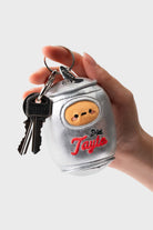 Hand holding a silver, plush keychain in the shape of a soda can, with keys attached. The can has a cartoon face and embroidered red script that reads "Diet Tayto."