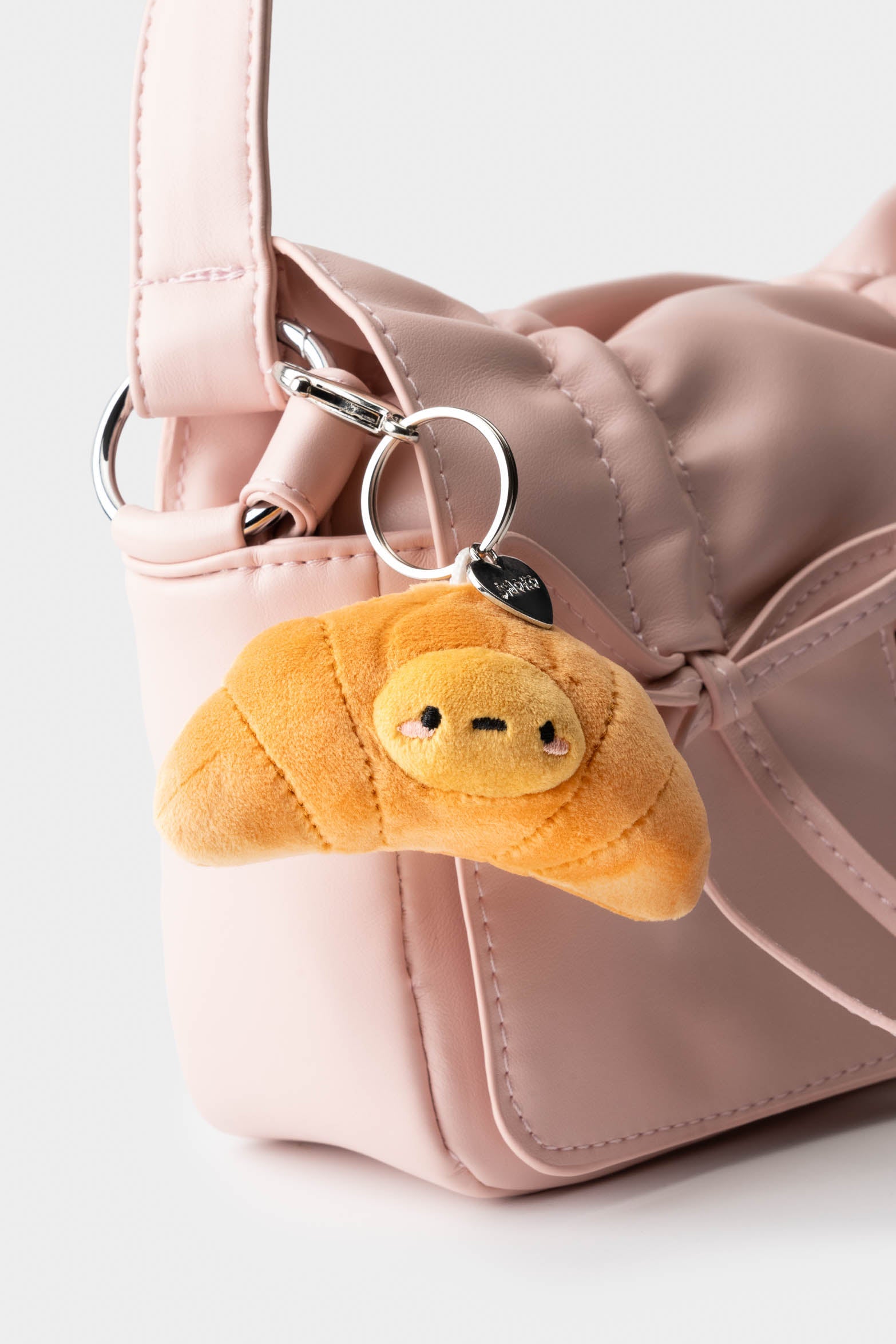 Pink purse with croissant keychain.