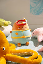 A plush toy character wearing a red snorkel mask and a blue and yellow swimsuit with a star.