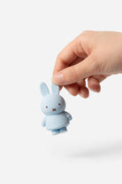 Hand holding a light blue Miffy toy rabbit.