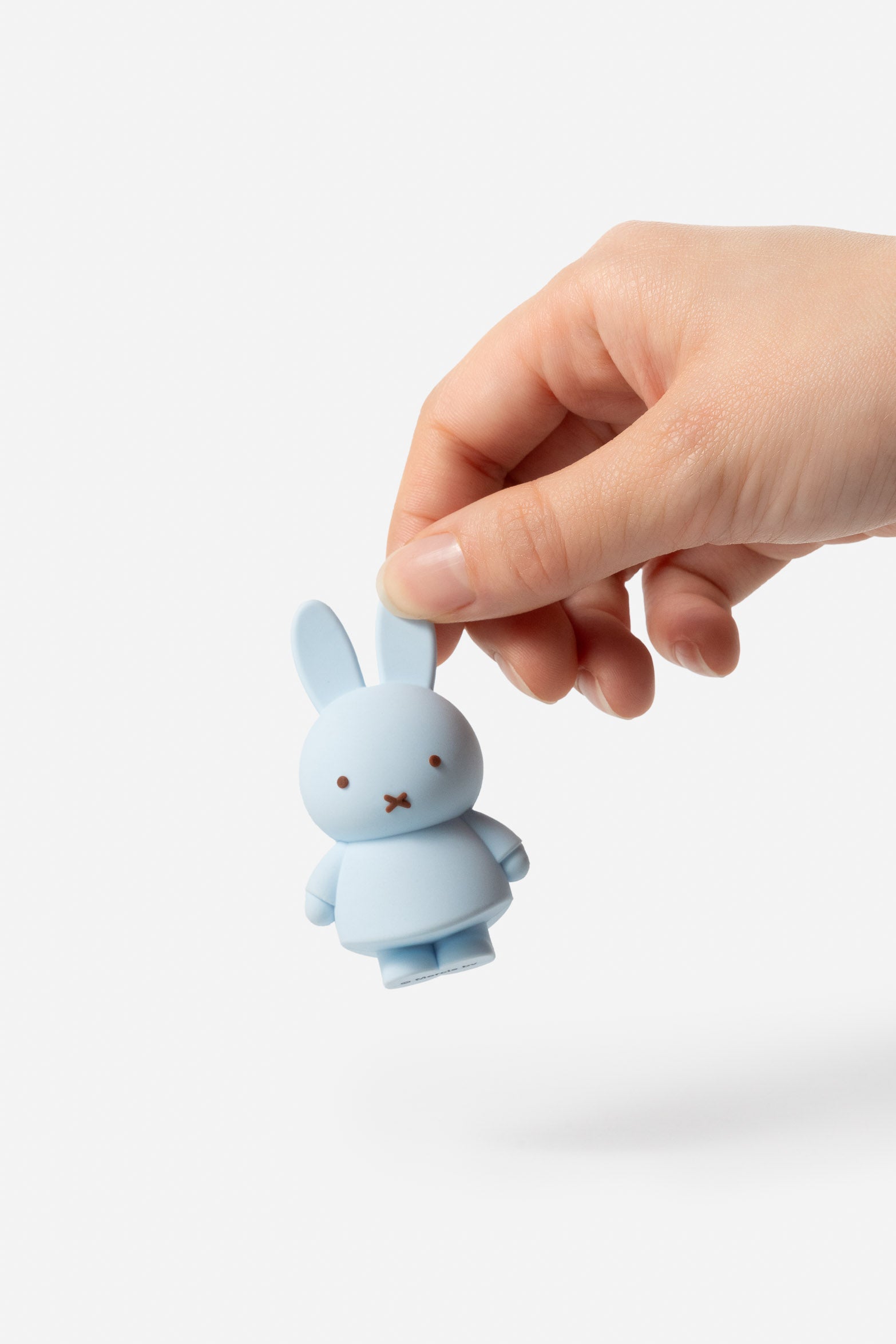 Hand holding a light blue Miffy toy rabbit.