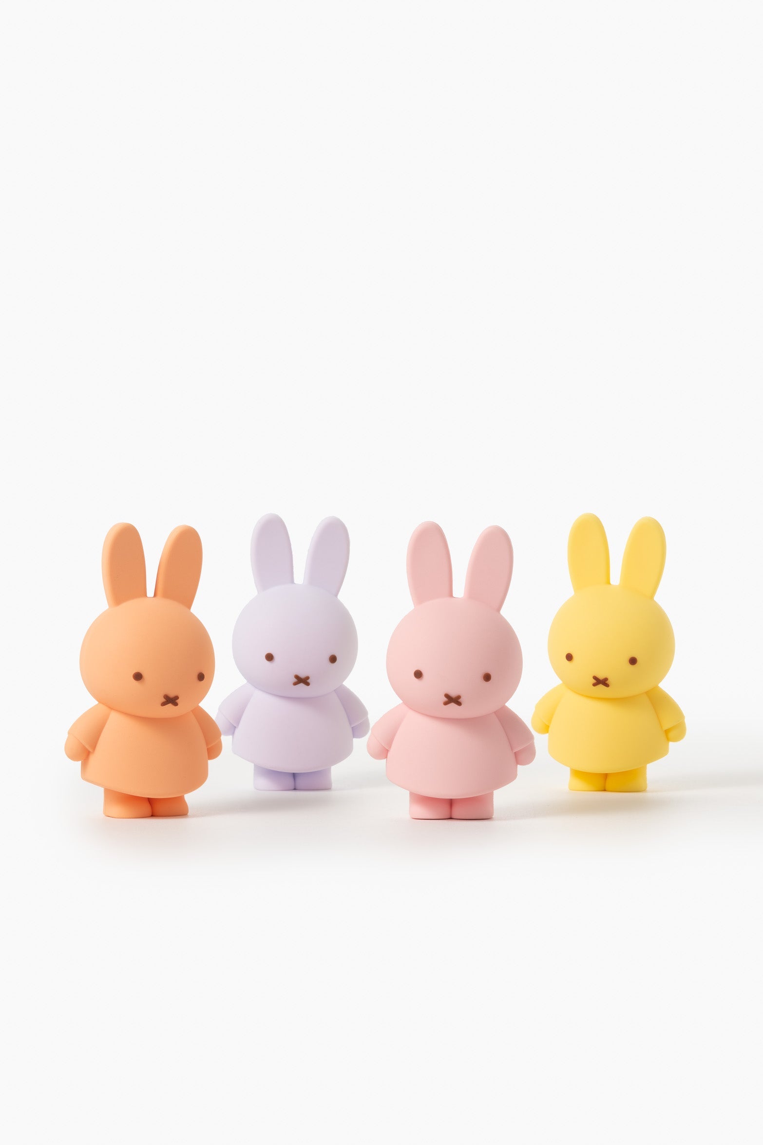 Four pastel-colored Miffy bunny figurines standing in a row on a white surface.