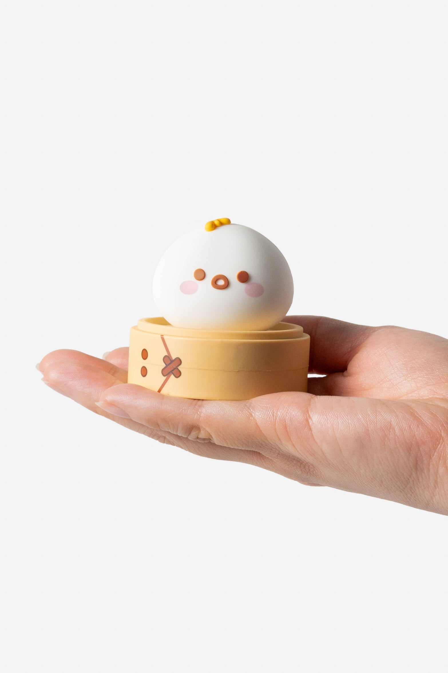 Hand holding a dim sum-shaped figurine.