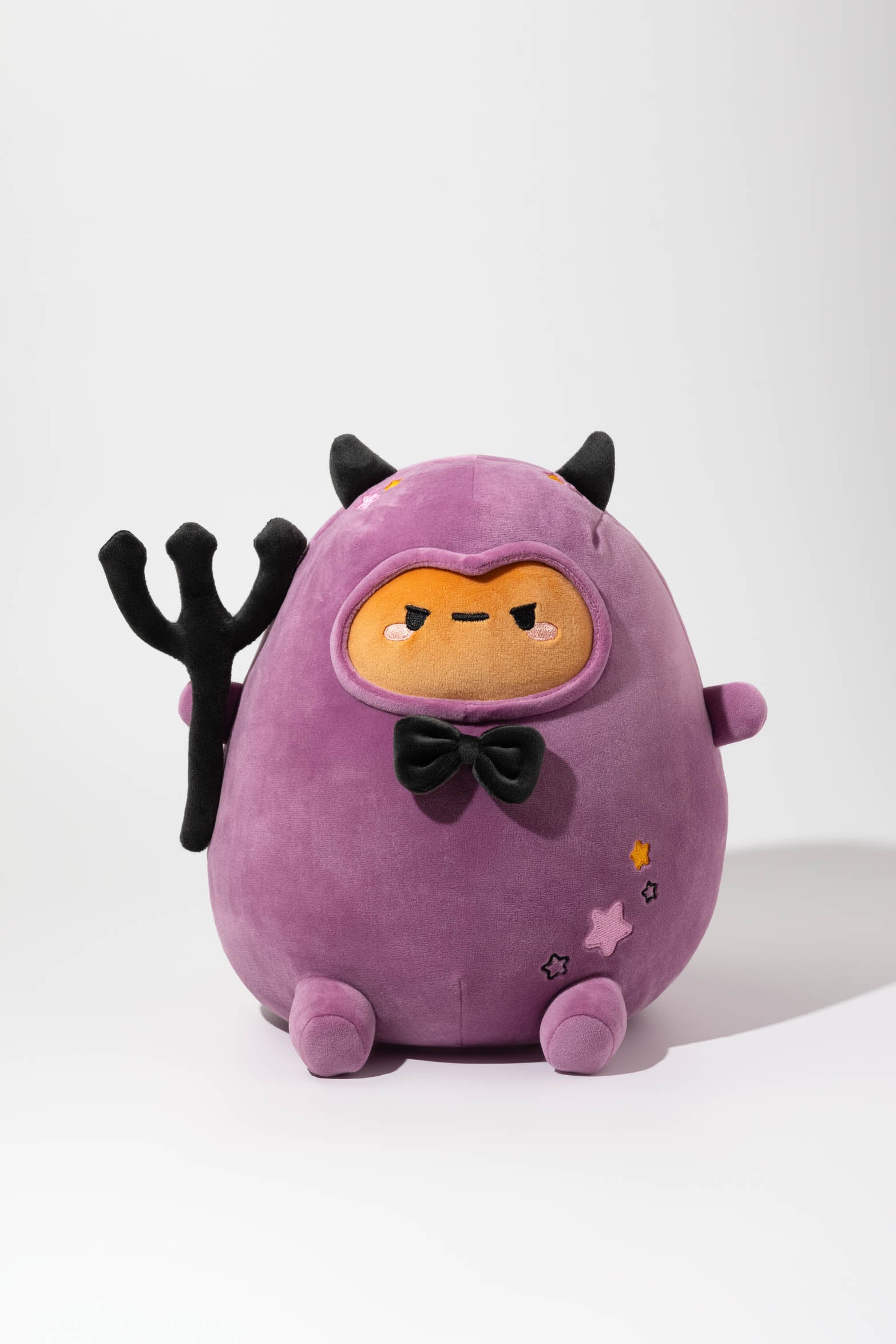 Purple plush toy in a devil costume with horns, bowtie, and trident.