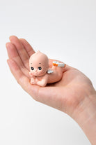 Small figurine of a baby held in a hand against a white background
