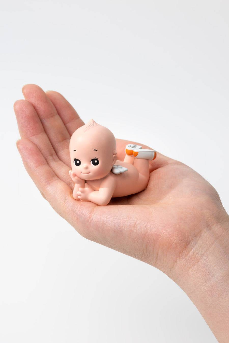 Small figurine of a baby held in a hand against a white background