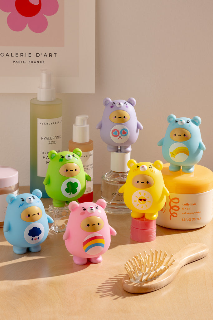 An array of colorful, bear-shaped containers with symbolic images, set among personal care products and a wooden hairbrush.