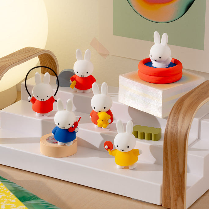 Set of small rabbit figurines on a white and wooden shelf with colorful decorations.