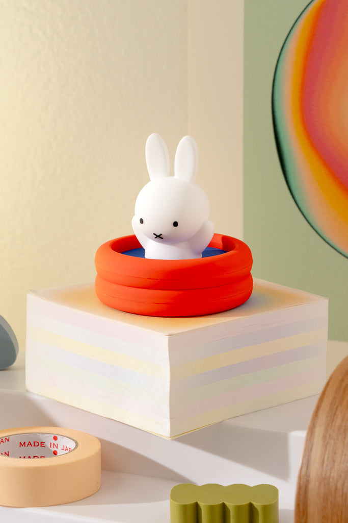 White rabbit figurine in a red basket on a wooden block with a colorful background