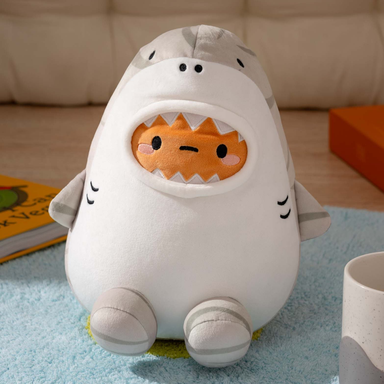 Plush shark toy with orange character in its mouth.