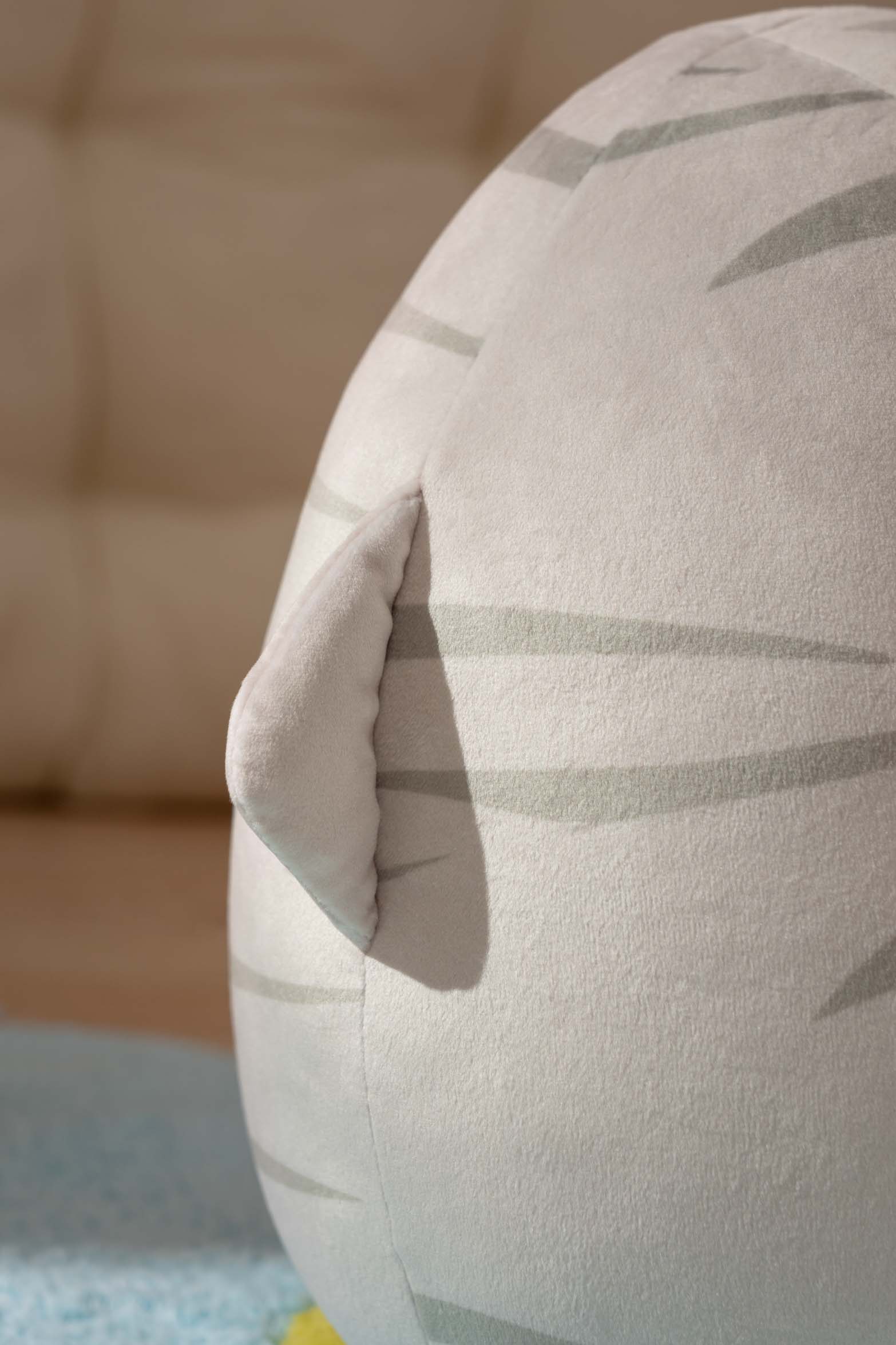 Close-up of a gray and white striped stuffed animal with an ear.