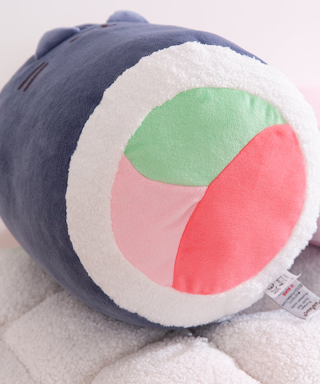Plush toy resembling a shark with a colorful circular design on a soft surface
